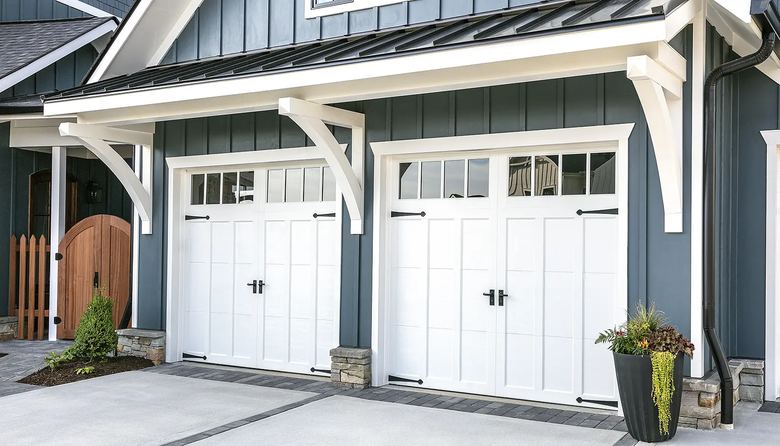 White carriage house garage doors with window tops on a dark blue home