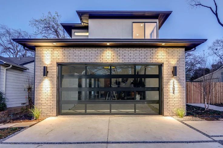 Full-view glass garage door in a dark aluminum frame on a modern brick home